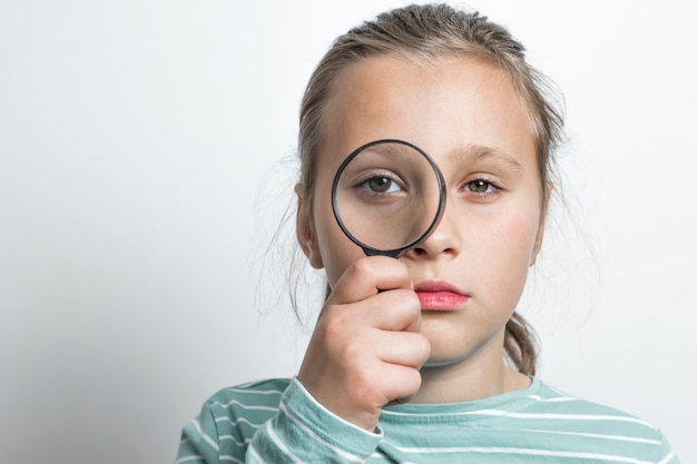 La fille regarde d&#39;un œil à la loupe.