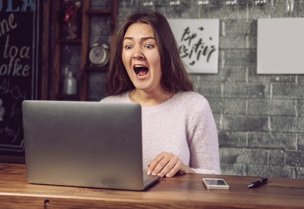 La fille regarde l'ordinateur portable avec horreur, fille terrifiée