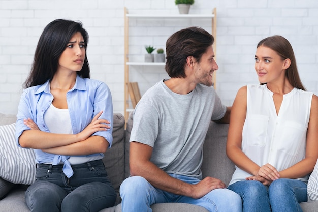 Une fille regarde son petit ami flirter avec une femme assise sur le canapé.