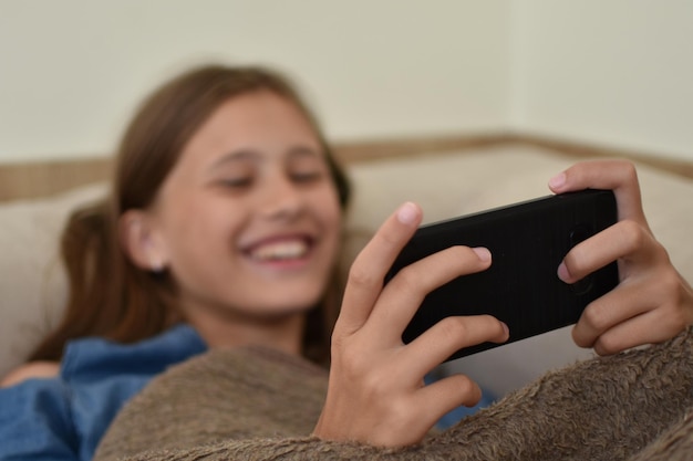 La fille regarde le téléphone. fille enfant joue en ligne dans un smartphone.