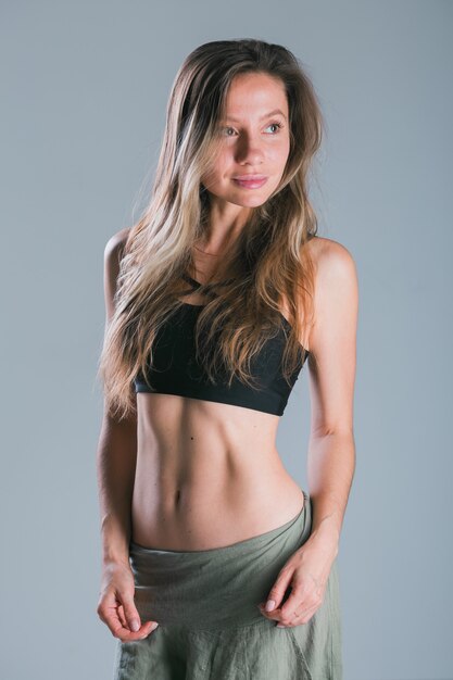 Fille de remise en forme avec un corps sportif posant au studio sur fond gris modèle souriant de remise en forme dans