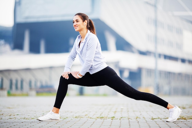 Fille de remise en forme Coureur de femme jeune fitness qui s'étend des jambes avant de courir