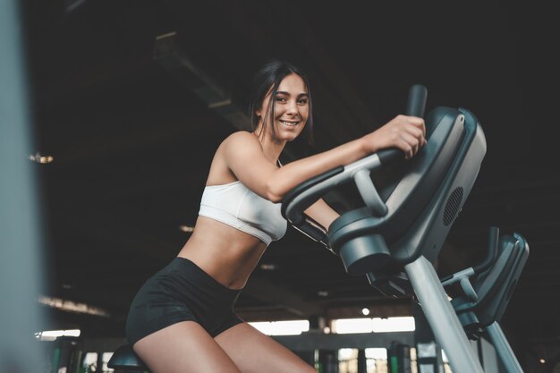 Fille de remise en forme est engagée sur un vélo stationnaire.