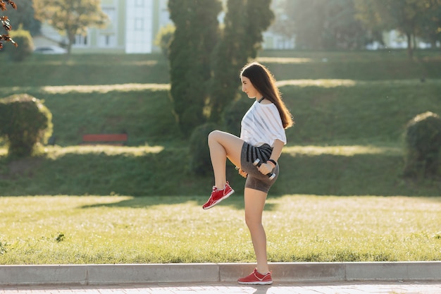 Fille de remise en forme faisant des exercices avec des haltères au coucher du soleil sur l&#39;herbe à l&#39;extérieur