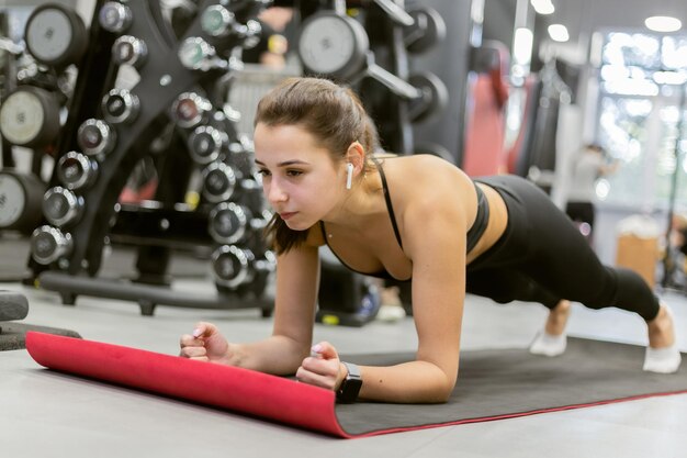 Fille de remise en forme pratiquant l'exercice de planche dans une salle de sport moderne