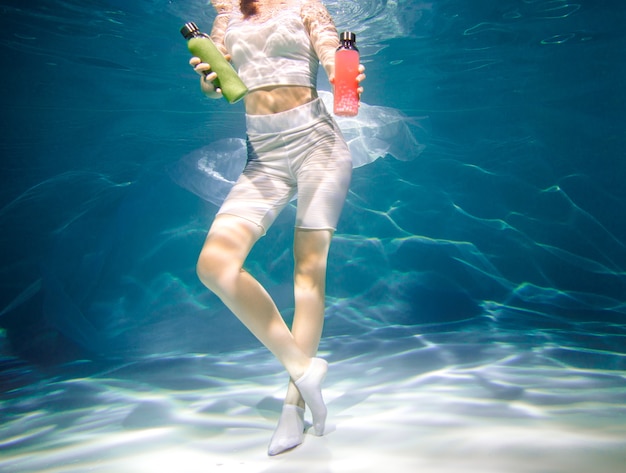 Fille de remise en forme avec smoothie coloré. Fraîcheur sous l'eau, nage et plonge.