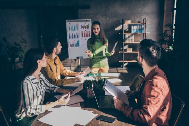 Fille réussie positive présente sa stratégie de développement de l'entreprise partenaires partenaires partenaires s'asseoir table de bureau tenir des documents documents