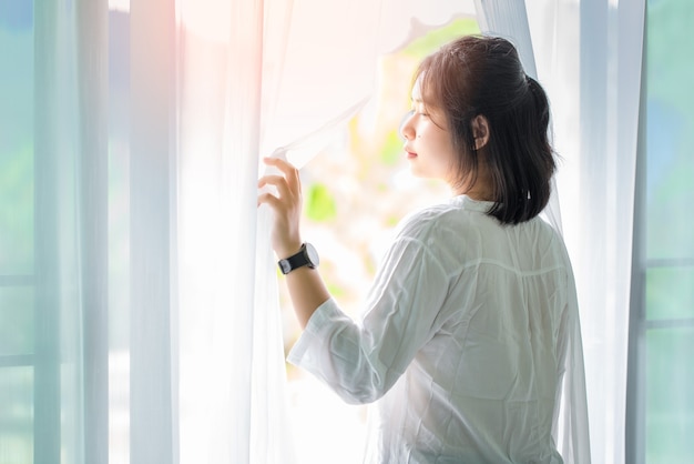 Fille, réveille-toi et ouvre les rideaux le matin pour prendre l'air.