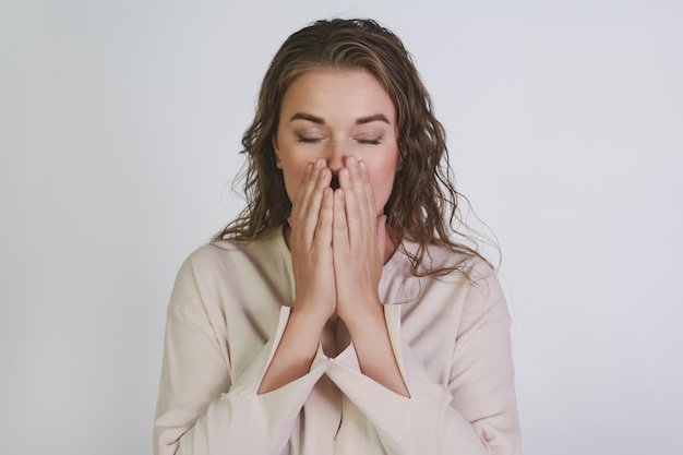 Une fille avec un rhume ou une allergie couvre sa bouche avec ses paumes sur le point d'éternuer