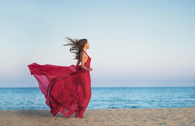 Fille en robe aérée courant le long de la plage