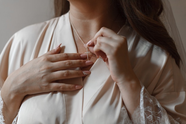 Fille en robe beige avec chaîne dorée autour du cou. mariée fixe une décoration de bijoux sur le cou. détails de mariage. détails du pendentif pour le cou des femmes. accessoires femme