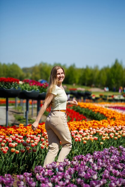 Une fille en robe blanche court parmi les tulipes Champ de tulipes jaunes et rouges