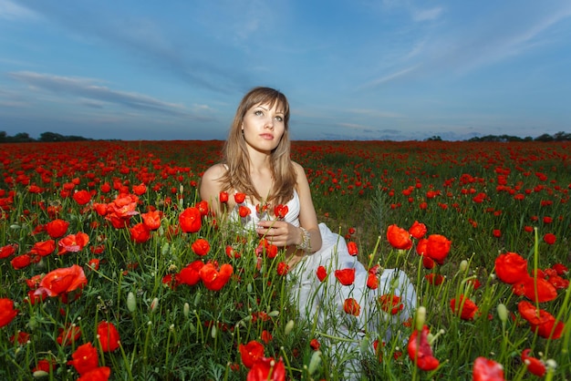 Fille en robe blanche dans le champ de coquelicots