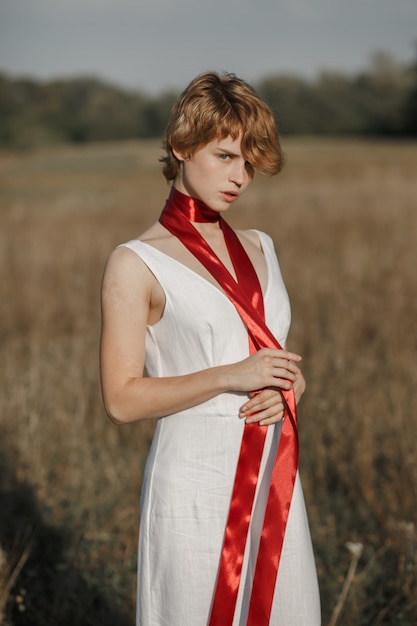 Fille en robe blanche avec un ruban rouge