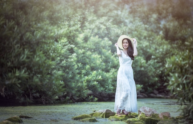 Une fille en robe blanche se dresse dans la forêt.