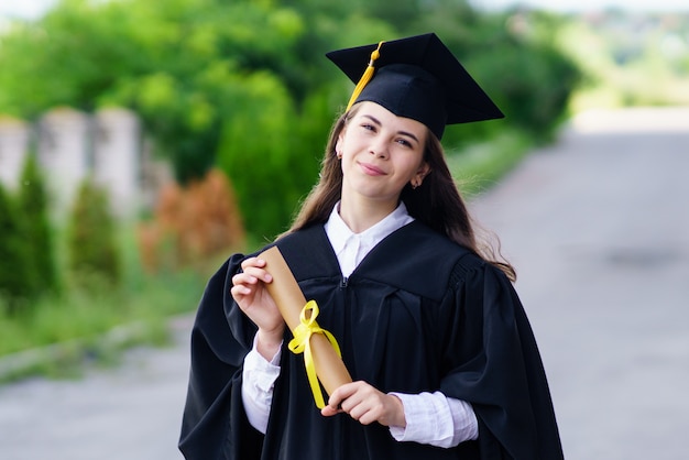 Fille en robe et bonnet tenant un diplôme