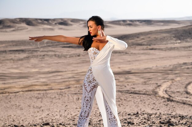 Fille en robe dans le désert ensoleillé. Mode de mariage et salon de beauté. Mariée et cérémonie de mariage. Modèle d'élégance et de mode. Femme en robe blanche dans les dunes de sable.