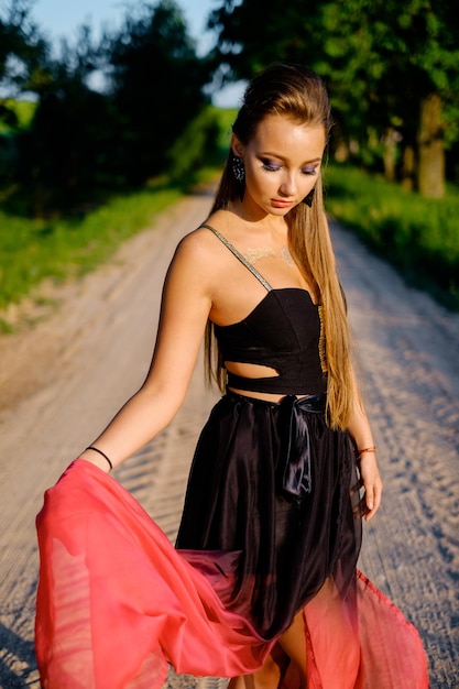 Fille en robe d'été sur une route de campagne