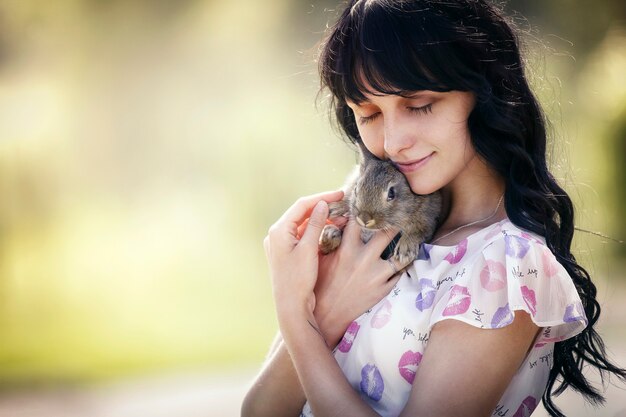 Fille en robe avec un lapin dans le parc