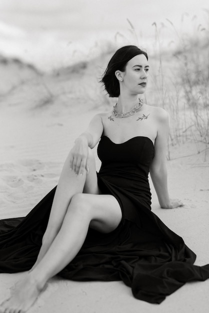 Fille en robe longue noire dans un désert de sable