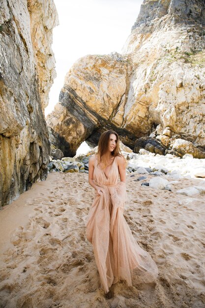 Fille en robe longue près des rochers et de l'océan