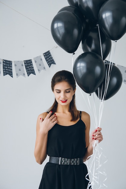 Fille en robe noire avec des ballons noirs