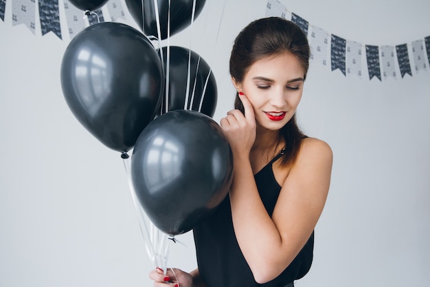 Fille en robe noire avec des ballons noirs