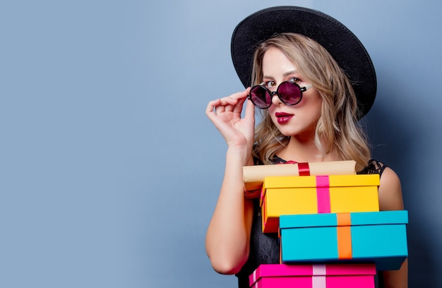 Fille en robe noire et chapeau avec des coffrets cadeaux