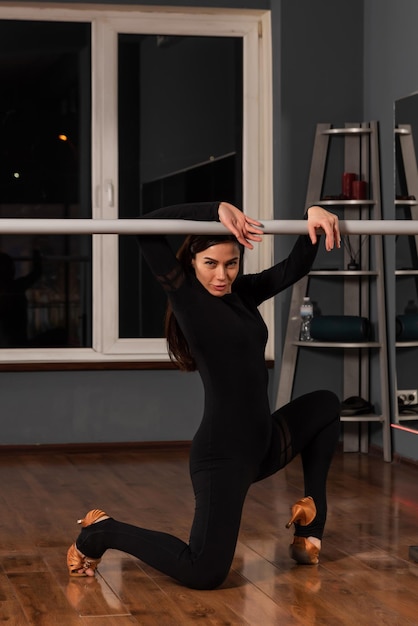 Une fille en robe noire s'entraîne dans un studio de danse