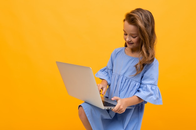 Fille en robe avec un ordinateur portable sur ses genoux sur un jaune avec copie espace