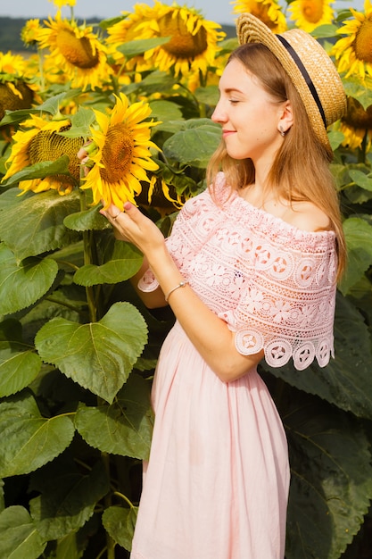 Fille en robe parmi les tournesols, la jeune fille se tient dans un champ de tournesols