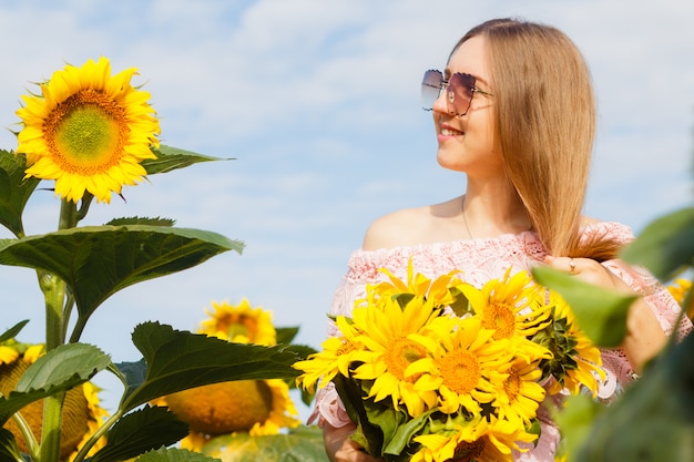 Fille en robe parmi les tournesols, la jeune fille se tient dans un champ de tournesols