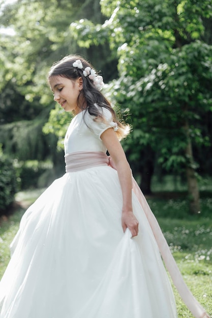 Fille en robe de première communion marchant dans le parc