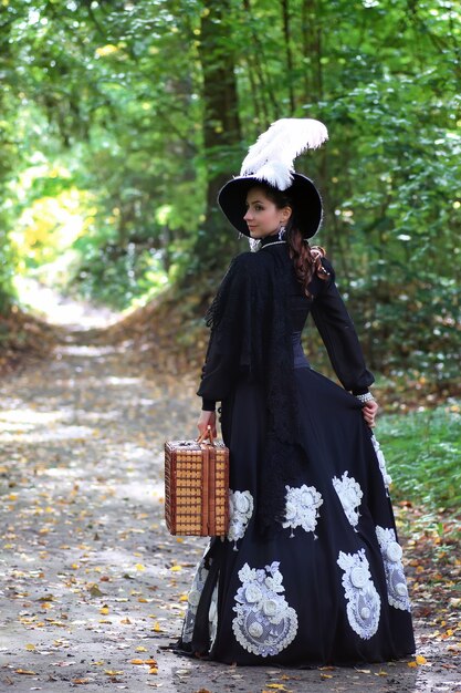 Photo fille en robe rétro 18e siècle avec valise en park