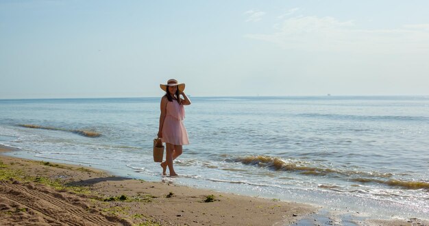 Fille en robe rose allant sur les vagues de la mer à midi