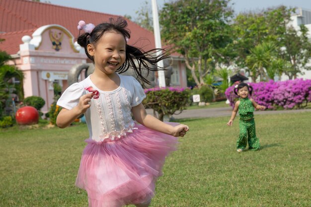 Une fille robe rose jouant avec bonheur dans le jardin