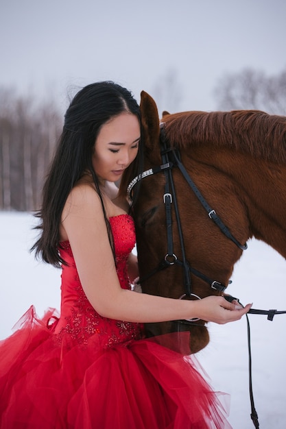 Fille en robe rouge, avec un cheval, hiver, brune, froid