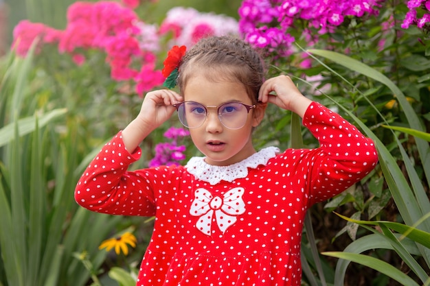 Une fille en robe rouge à pois blancs tient des lunettes