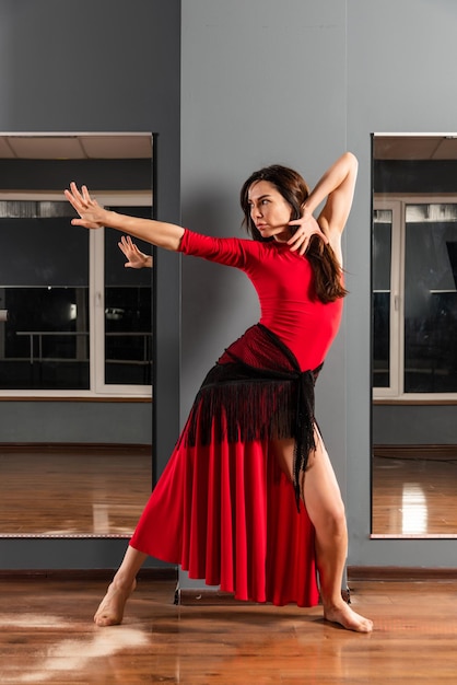 Une fille en robe rouge s'entraîne dans un studio de danse