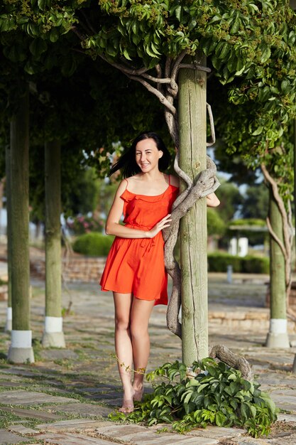 Fille en robe rouge se tient près d&#39;un bel arbre