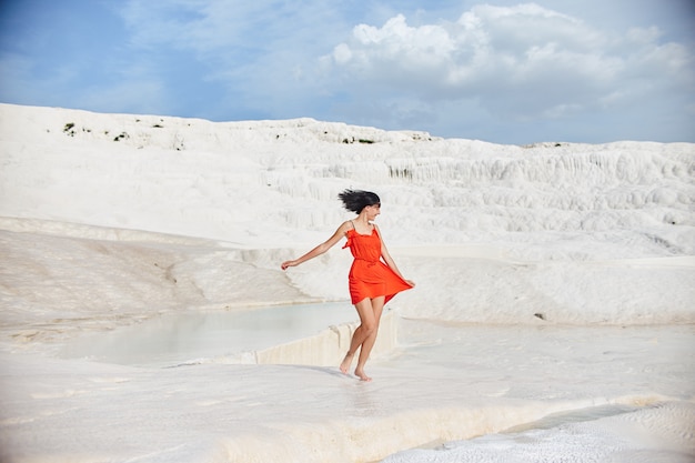 Fille en robe rouge sur travertins blancs