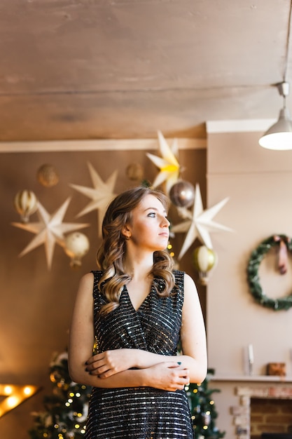 Fille en robe sombre du soir et arbre de Noël