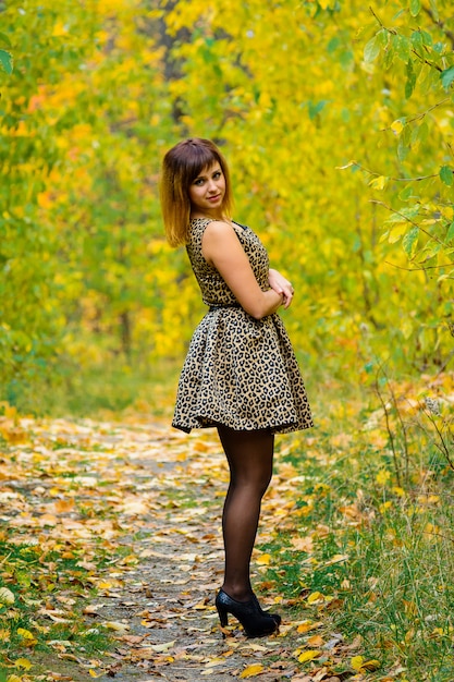 Fille en robe et talons posant à l'automne