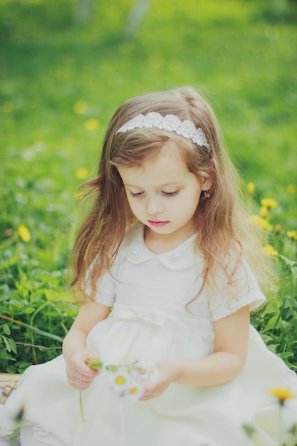 Une fille en robe tient un bouquet de marguerites dans un jardin de cerisiers de printemps