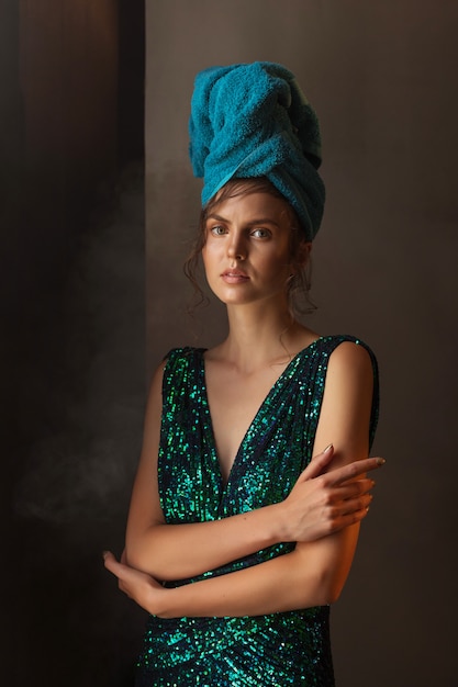 Fille en robe vert-bleu brillant et serviette sur la tête