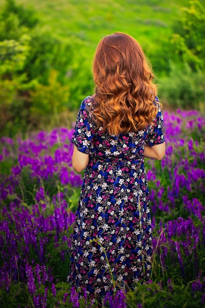 Une fille en robe violette sur fond de fleurs bleues