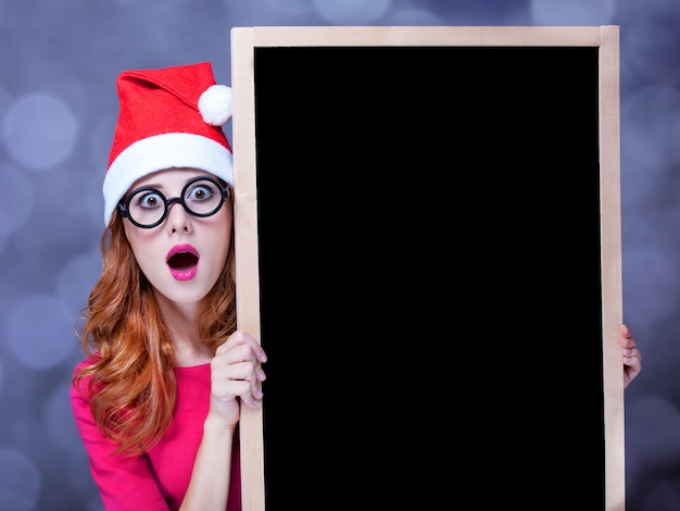 Photo fille rousse au chapeau de noël avec tableau noir