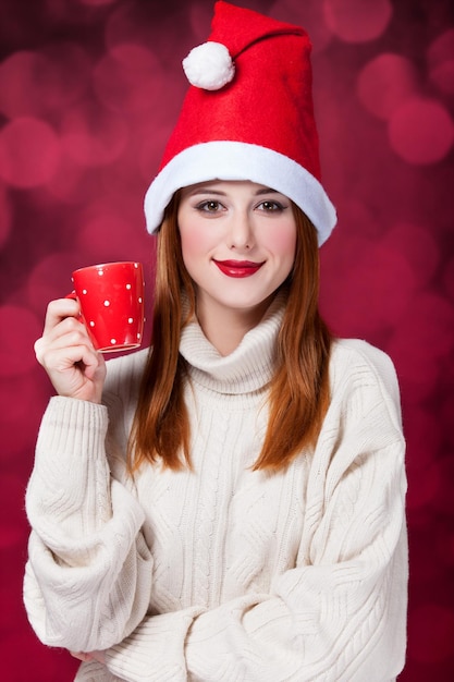 Fille rousse au chapeau de Noël avec tasse