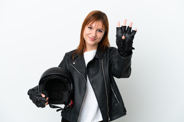 Fille rousse avec un casque de moto isolé sur fond blanc heureux et comptant quatre avec les doigts