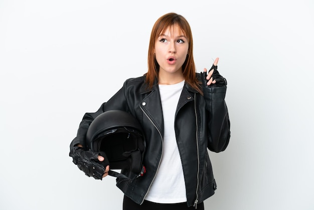 Fille rousse avec un casque de moto isolé sur fond blanc pensant une idée pointant le doigt vers le haut